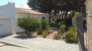 A residential area with a white building, a tiled roof, and a garden with various plants and trees. - Villa Los Balconess,<br>Is available from  6 nights (Torrevieja)