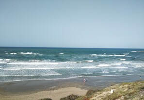 A beach with waves and two people walking.