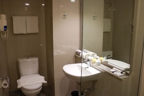 Un baño moderno con inodoro, lavamanos y cabina de ducha de vidrio.
