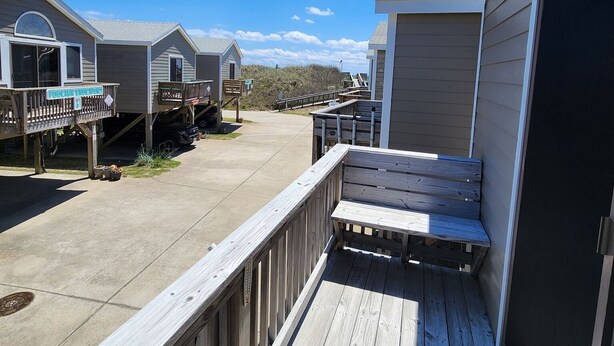 A beachfront property with multiple cabins, a wooden deck, and a clear sky.