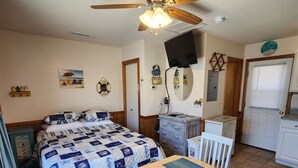 A bedroom with a bed, a ceiling fan, a television, a desk, and a chair. - Put your Anchor down with Nautical Nine! Beachfront, Pet Friendly Cabana! (HATTERAS)