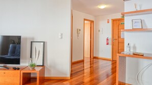 A modern hotel lobby with a wooden floor, a flat-screen TV, a small plant, and a reception desk. - Levada dos Piornais, a Home in Madeira (Funchal)