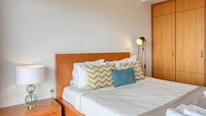 A neatly made bed with a wooden headboard, a bedside lamp, and a wardrobe. - Levada dos Piornais, a Home in Madeira (Funchal)
