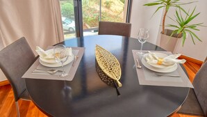 A round dining table with two chairs, a woven centerpiece, and a glass of water on each side. - Levada dos Piornais, a Home in Madeira (Funchal)