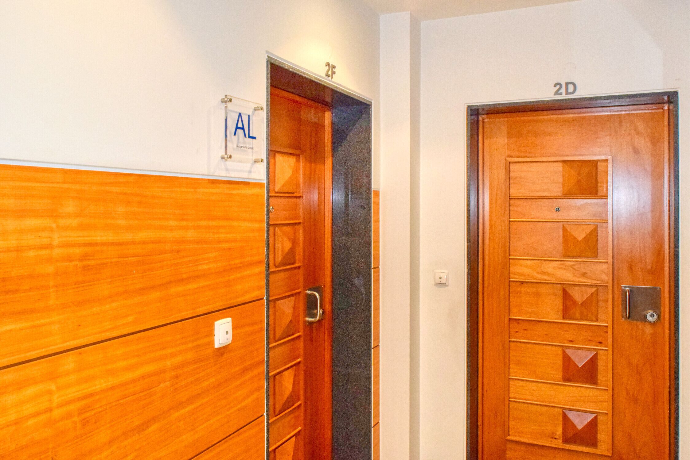 Deux portes en bois, avec une enseigne au-dessus de la porte de gauche indiquant « AL » et une autre au-dessus de la porte de droite indiquant « 2D ».