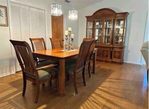 A dining area with a wooden table and chairs, a chandelier, and a china cabinet.