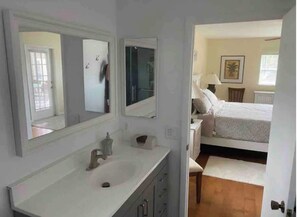 A bedroom with a bed, a bedside table, a lamp, and a window.