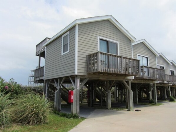 A two-story house with a balcony on the upper floor, supported by wooden stilts. - Beach Escape is a cool and calm get-a-way! (HATTERAS)