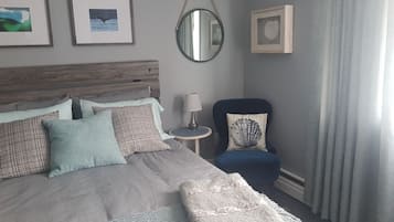 A bedroom with a bed, a chair, a round mirror, and framed pictures on the wall.
