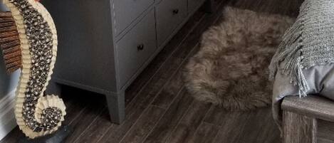A room with a gray dresser, a wooden chair, a fluffy rug, and a wall clock.
