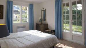 Ein Schlafzimmer mit Bett, Kommode, Spiegel und einem Fenster mit Vorhängen.