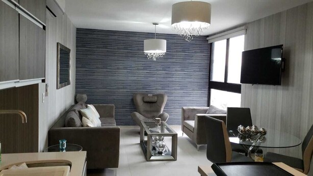 A modern living room with a sofa, armchairs, a coffee table, and a TV mounted on the wall. - Comfortable private room (Lomas de San Francisco)