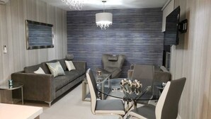 A modern living room with a sofa, armchairs, a glass coffee table, and a TV mounted on the wall. - Comfortable private room (Lomas de San Francisco)