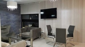A modern living room with a sofa, two armchairs, a coffee table, and a TV mounted on the wall. - Comfortable private room (Lomas de San Francisco)