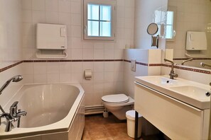 A bathroom with a bathtub, toilet, sink, and a window. - Villa with garden near beautiful golf course (Vasles)