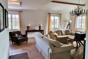 A living room with a sofa, armchair, and a small table with lamps. - Villa with garden near beautiful golf course (Vasles)