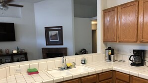 Una cocina con encimera blanca, armarios de madera, un fregadero y una cafetera.