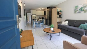 Un salon moderne comprenant un canapé, une table basse et un coin repas avec des chaises.