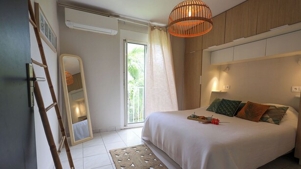 Une chambre à coucher avec un lit, une table de chevet, une lampe et une vue sur l’extérieur.