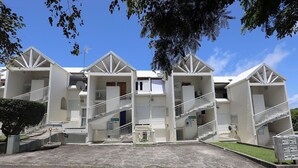 Une rangée de bâtiments blancs à plusieurs étages, dotés de balcons et d’escaliers.