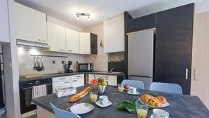 Une cuisine moderne avec un coin repas, équipée d’un four à micro-ondes, d’un four traditionnel et d’un réfrigérateur.
