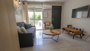 Un salon avec un canapé, une table basse, un téléviseur et une porte.