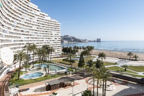 A hotel with a curved facade, a pool, palm trees, and a beach view. - FLORAZAR 1, I-A 7-B (Cullera)