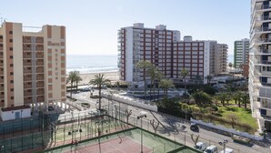 Ein Hochhaus mit Blick auf den Strand, einem Tennisplatz und einem Parkplatz.