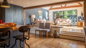 A modern kitchen with a blue accent wall, wooden beams, and a dining area with a wooden table and chairs. - Heath Cottage, Mattishall, Dereham , Norfolk (Mattishall)