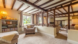 A cozy living room with exposed wooden beams, a fireplace, and a bookshelf filled with books. - Heath Cottage, Mattishall, Dereham , Norfolk (Mattishall)