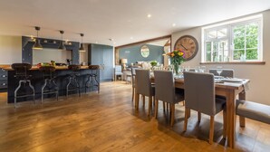A modern kitchen with wooden flooring, a dining area with a wooden table and chairs, and a large window with a view of greenery. - Heath Cottage, Mattishall, Dereham , Norfolk (Mattishall)