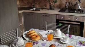 A breakfast setup with pastries, juice, and a pie on a table in a kitchen with cabinets and a stove. - Trilocale 150mt from the sea of La Caletta of Siniscola Nuoro Sardinia Italy (La Caletta)