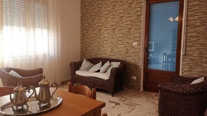 A cozy living room with wicker furniture, a stone wall, and a door with a window. - Trilocale 150mt from the sea of La Caletta of Siniscola Nuoro Sardinia Italy (La Caletta)