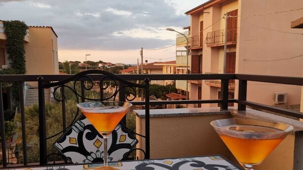 A balcony with a table set for two, featuring a martini glass and a plate with olives, bread, and nuts. - Trilocale 150mt from the sea of La Caletta of Siniscola Nuoro Sardinia Italy (La Caletta)