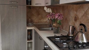 A kitchen with a gas stove, a kettle, and a sink. There are cabinets and a countertop. - Trilocale 150mt from the sea of La Caletta of Siniscola Nuoro Sardinia Italy (La Caletta)