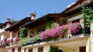 A row of traditional buildings with balconies adorned with flowering plants. - Beautiful View in a Shabby Chic Atmosphere (Padenghe Sul Garda)