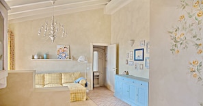 A cozy living room with a checkered sofa, a chandelier, and a blue cabinet.