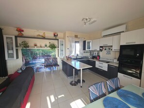 Een moderne keuken met een eethoek, een bank en uitzicht op een tuin.