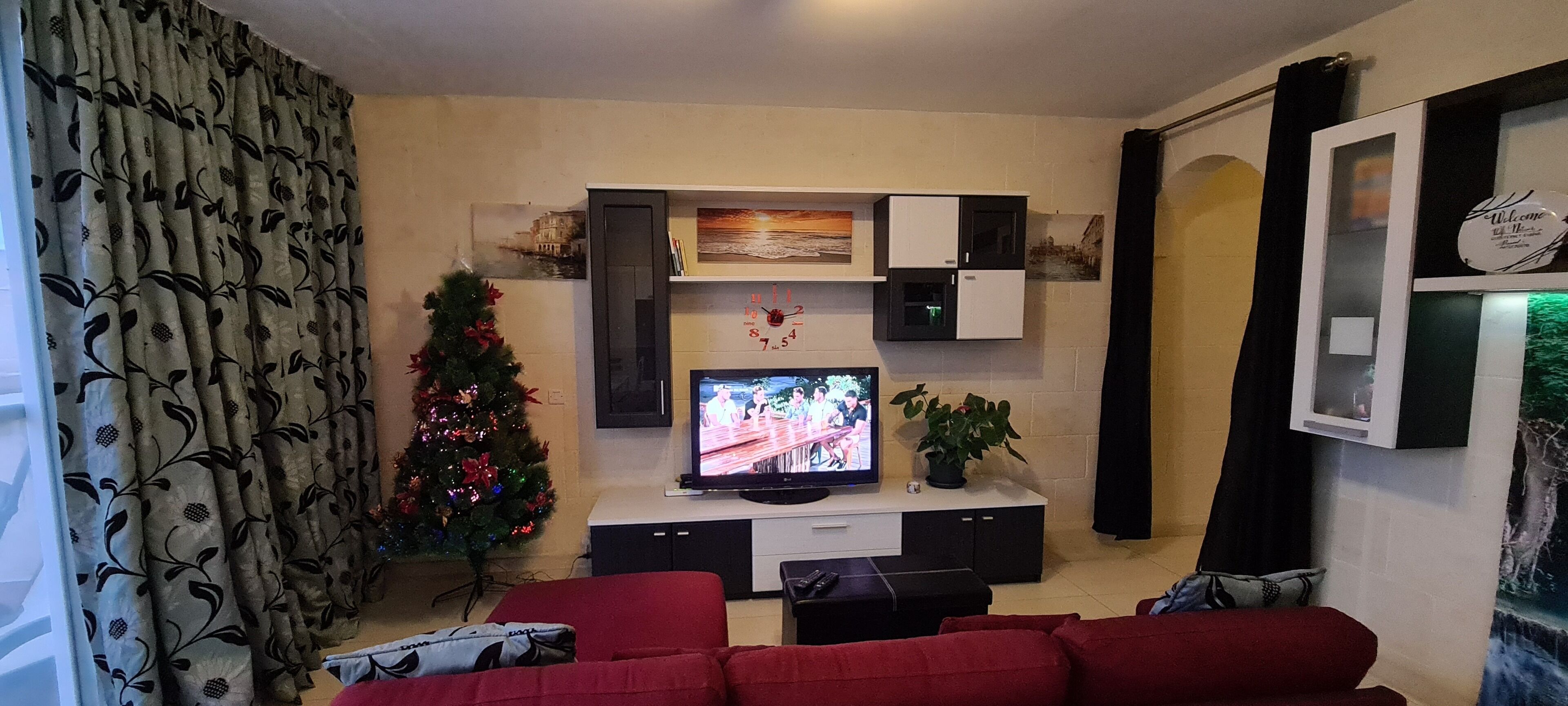 Una sala de estar con televisor, árbol de Navidad y sofá.