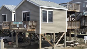 Una cabana a peu de platja amb terrassa, una petita escala i un senyal que indica que és una propietat privada.