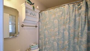 A bathroom with a toilet, sink, and a shower curtain with a sea shell pattern. - Escape to the beach with Cabana By The Sea! (HATTERAS)