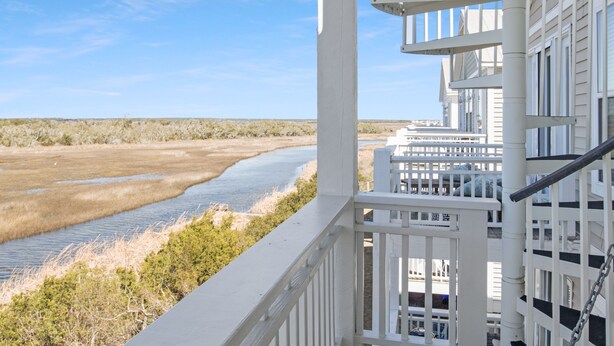 Un bâtiment blanc doté d’un balcon donnant sur une rivière et des marais.