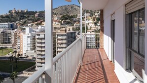 Un balcon donnant sur un paysage urbain et une colline parsemée de bâtiments.