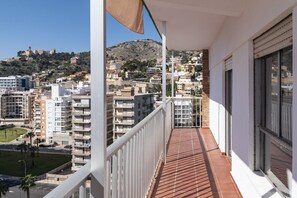 Un balcon donnant sur un paysage urbain et une colline parsemée de bâtiments.