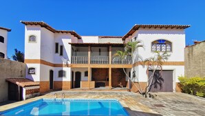 A two-story building with a swimming pool in the foreground. - Beautiful 5 Bedrooms (4 Suites) Air conditioning, swimming pool, barbecue - Saquarema (Saquarema)