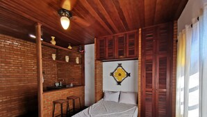 A room with a brick wall, a bed, a small kitchen area with stools, and a wooden ceiling. - Beautiful 5 Bedrooms (4 Suites) Air conditioning, swimming pool, barbecue - Saquarema (Saquarema)