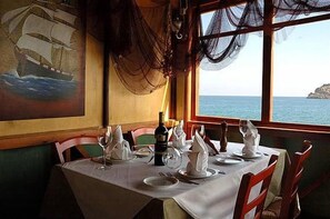 Mesa preparada para comer con vista al mar y un cuadro en la pared.