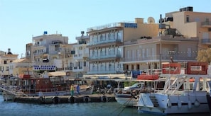 A waterfront with boats docked, a floating restaurant, and multi-story buildings. - Aristea Hotel (Agios Nikolaos)