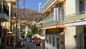 Vista de la calle con un hotel llamado 'Hotel Aristia' a la derecha, que cuenta con balcones y un letrero que indica que es un hotel.