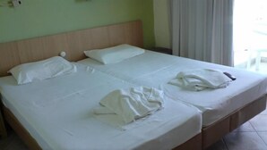 A double bed with white linens, a wooden headboard, and a small bedside table with a lamp. - Aristea Hotel (Agios Nikolaos)
